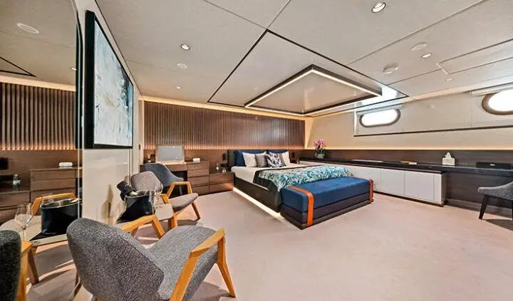 Master cabin with king bed and ensuite, cozy seating, warm lighting on yacht interior