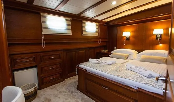 Dolce Vita yacht cabin with a queen bed, wooden cabinetry, and porthole window
