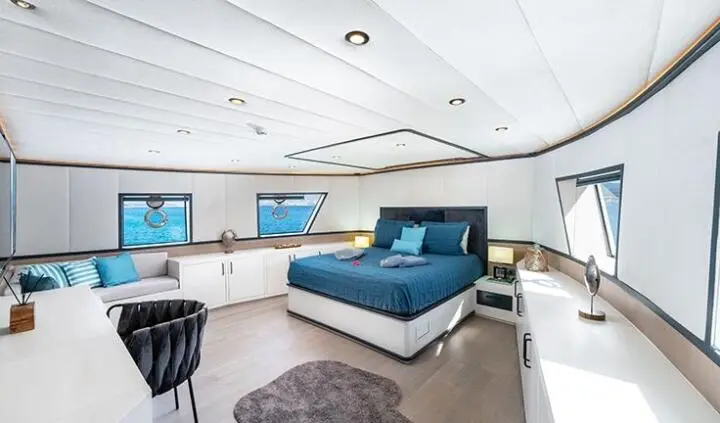 Calm Down yacht cabin with king bed and ensuite visible, seating area in foreground