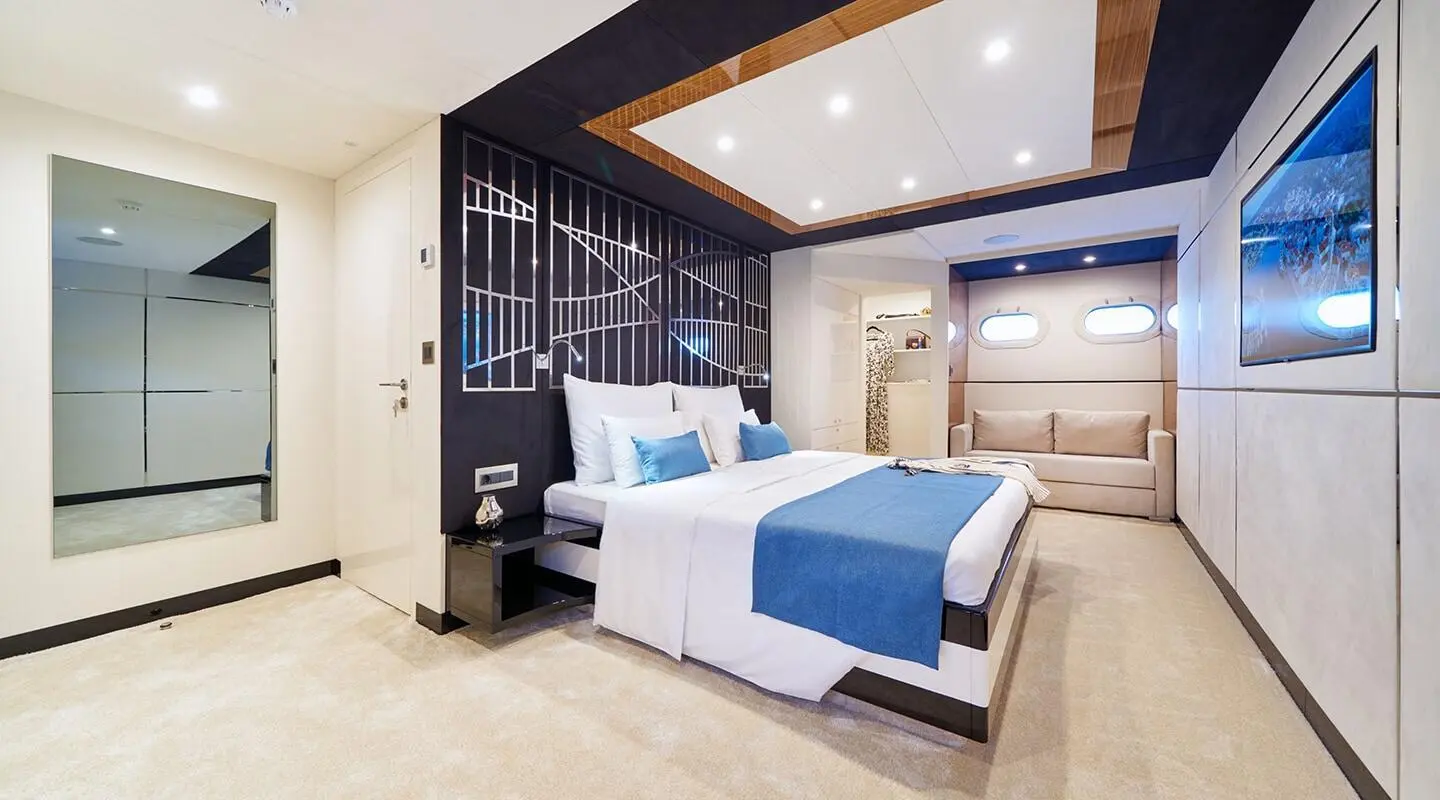 Acapella yacht master suite with large bed, blue accents, and built-in cabinetry