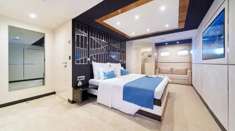 Acapella yacht master suite with large bed, blue accents, and built-in cabinetry