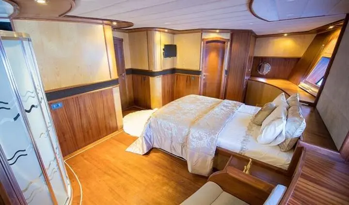 Nevra Queen cabin with king bed, white bedding, wood panels, bedside lamps