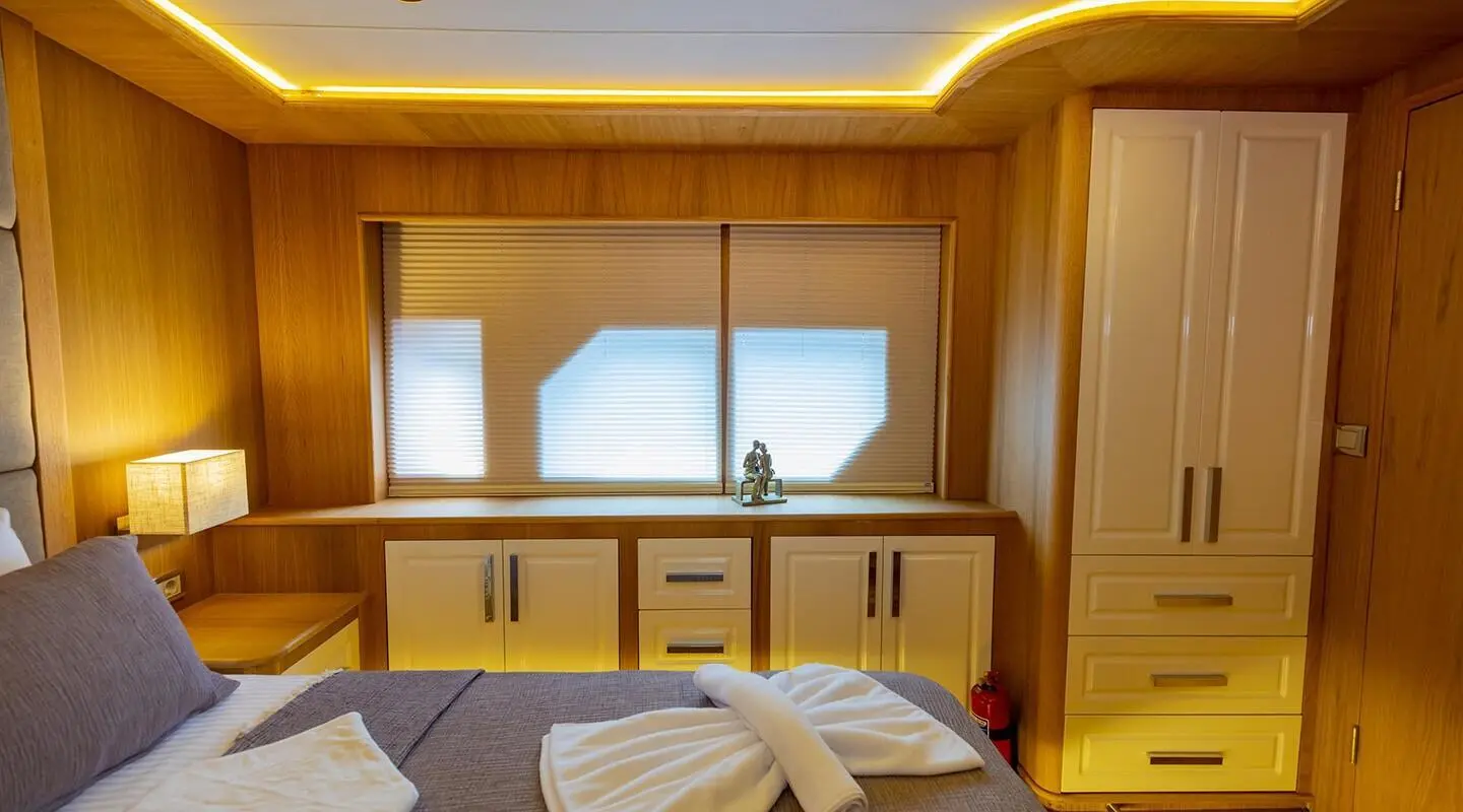 Luxurious yacht bedroom interior with bed, warm wood panels, and window view