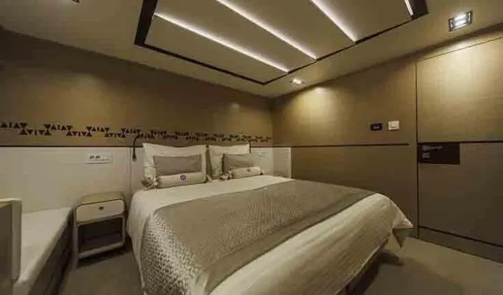 Omnia yacht cabin interior with plush bed, soft lighting, and built-in storage