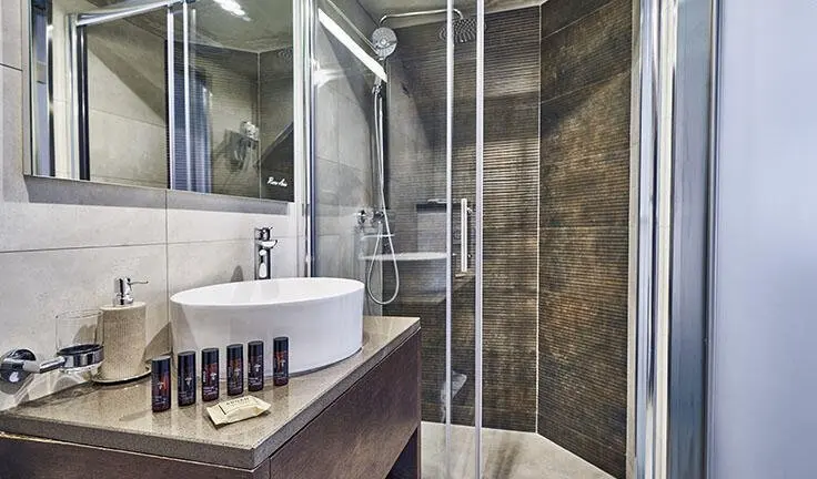 Bathroom onboard Rara Avis yacht: curved glass shower, white sink, tiled walls
