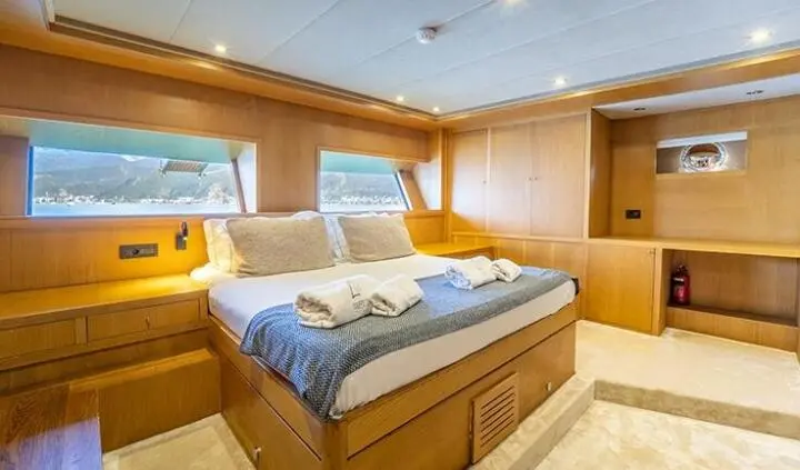 Master cabin with king bed, blue bedding, wooden panels, ensuite hint