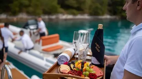 Yacht Anima Maris in turquoise water with fruit platters on a table foreground