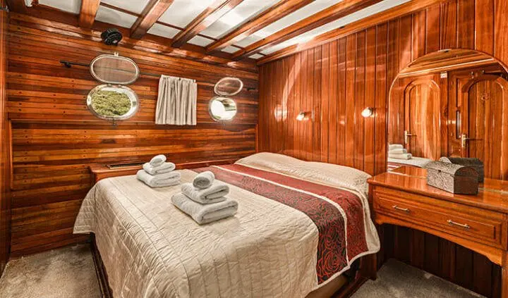 Two single beds in glossy wooden cabin with striped bed runners and towels