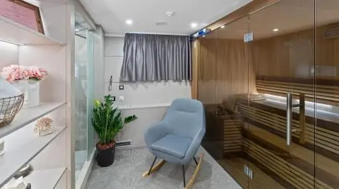 Interior lounge area of Freedom yacht with blue armchair, plants, and gray curtains