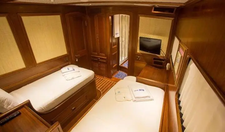 Twin wooden cabins with two single beds, towels, and a small bedside table
