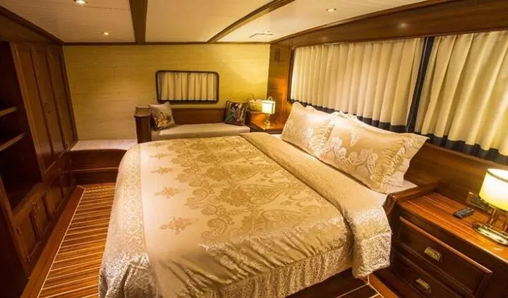 Master cabin with king bed, beige linens, wood headboard, ensuite doorway