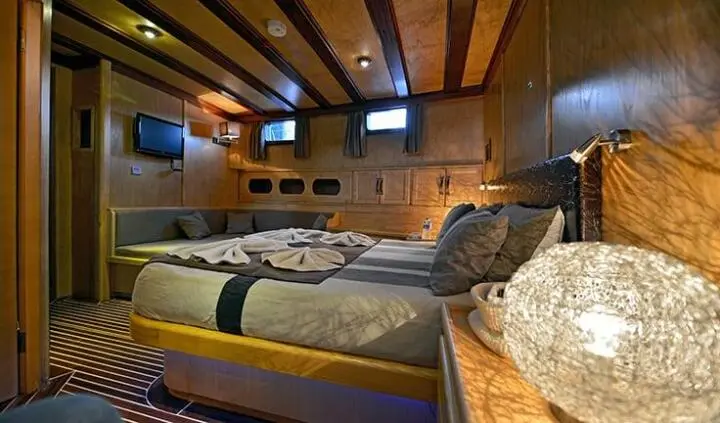 Master cabin with king bed, wooden beams, ensuite doorway, pillows and lighting