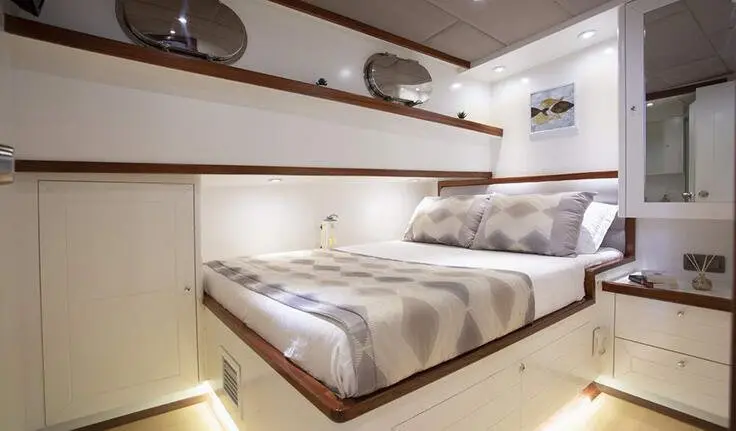 Twin bed cabin on Grand Sailor yacht with striped bedding and overhead cabinets