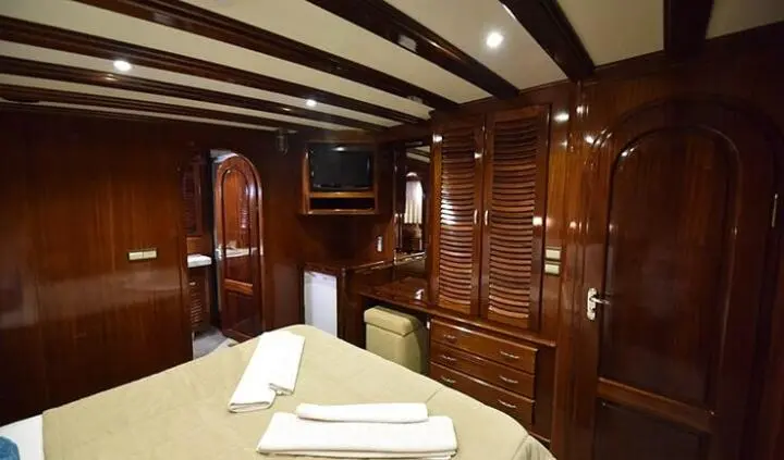 Interior cabin with wooden polished walls, doorway, and neatly made bed with white pillows