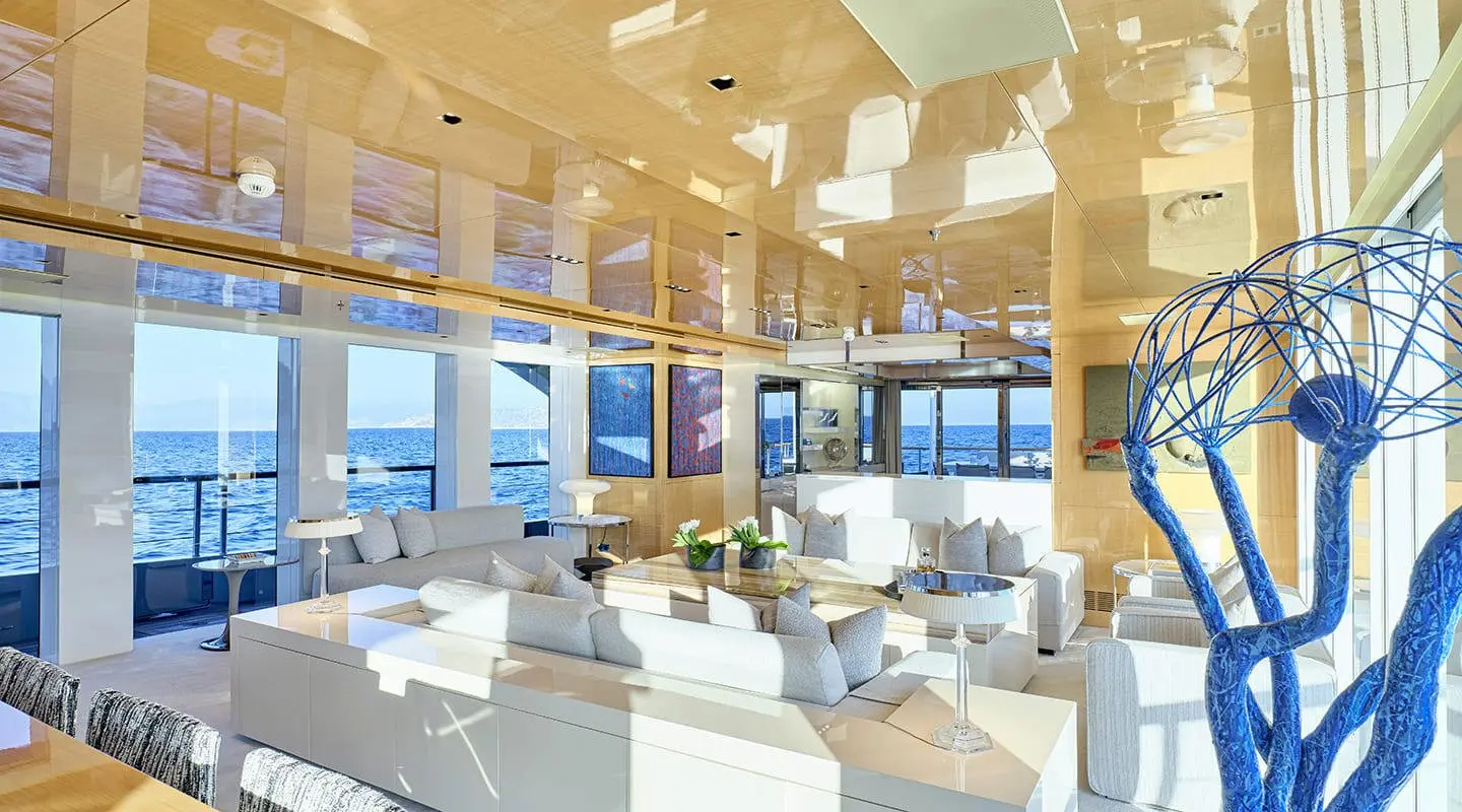 Luxurious indoor yacht lounge with white seating under warm lighting and large windows