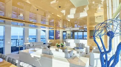 Luxurious indoor yacht lounge with white seating under warm lighting and large windows