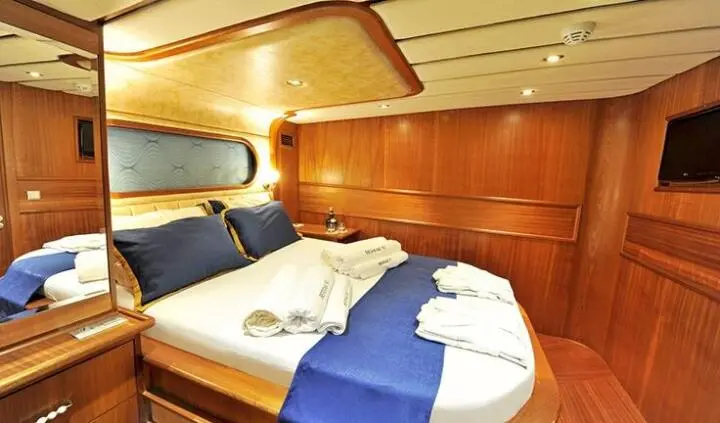 Double cabin on Berrak Su yacht with two neatly made beds and blue accents