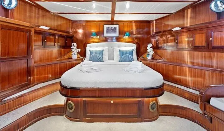 Elegant yacht master cabin with large bed, polished wood panels, and built-in nightstands