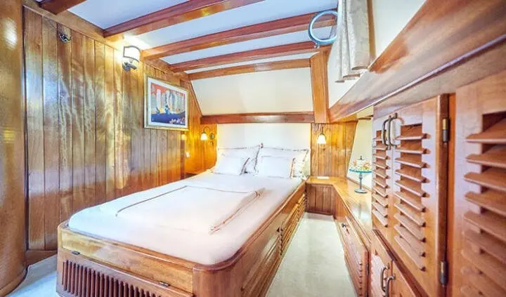 Master cabin with king bed, wood paneling, ensuite bathroom visible
