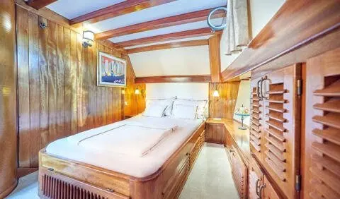 Master cabin with king bed, wood paneling, ensuite bathroom visible