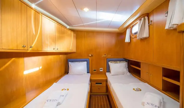 Twin cabin with two single beds, wood-paneled walls, and desks on each side