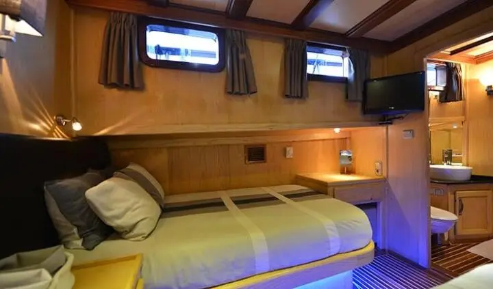 Twin cabin aboard Derin Deniz showing compact bed, porthole, and wood paneling