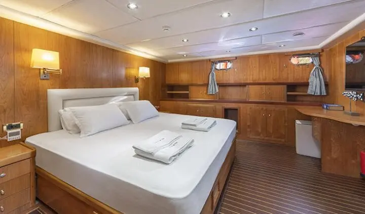 Twin bed cabin with bedside lamps and wooden cabinets along the walls