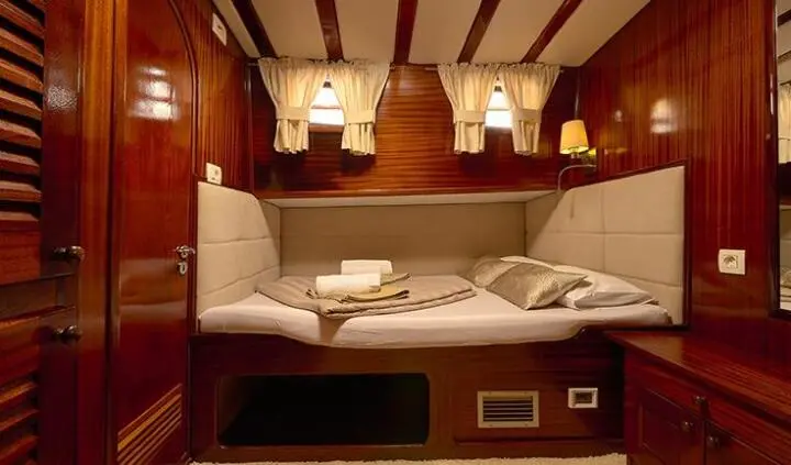 Cozy yacht cabin with two single berths, white bedding, and warm wood accents