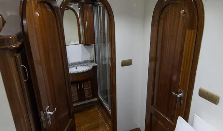 Image of a cabin interior on a yacht with a bed and wooden doors