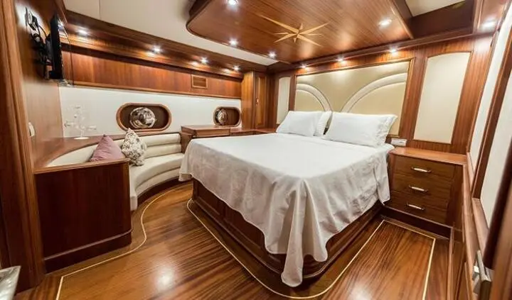 Halcon Del Mar cabin with two twin beds pushed together, wooden accents, porthole window, and soft lighting