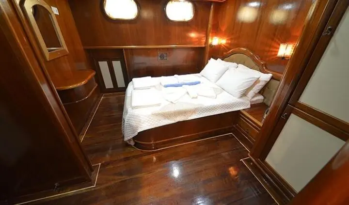 Twin bed cabin with white linens, wooden walls, and soft lighting on a yacht
