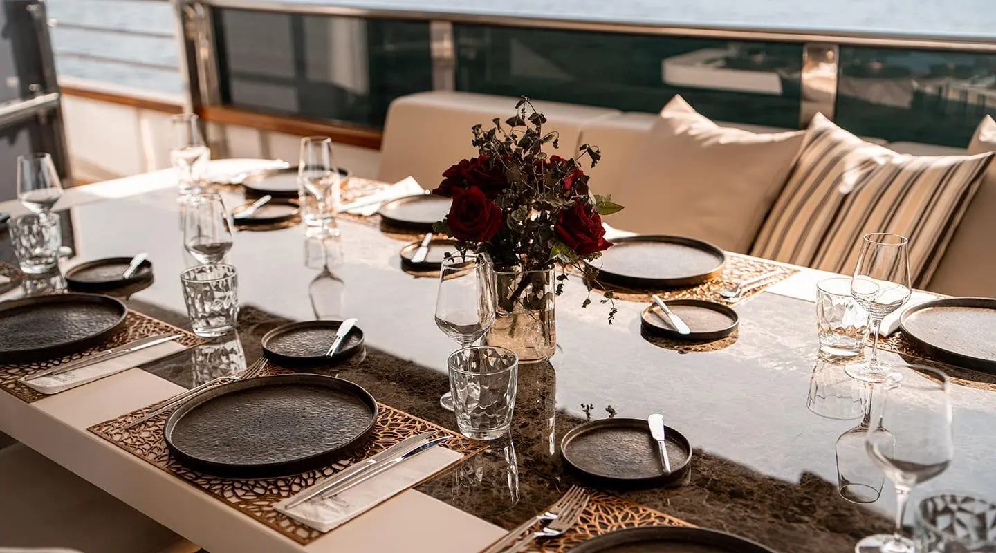 Elegant yacht Cristal dining setup on deck during sunset with tableware