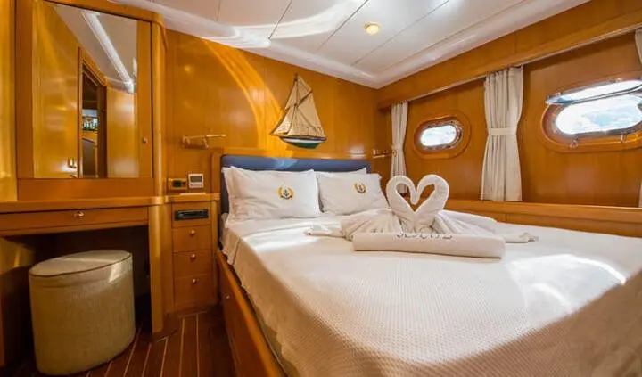 Two twin beds pushed together with white linens and heart towels in cabin