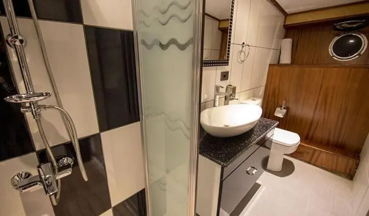 Compact luxe bathroom aboard Nevra Queen cabin with glass shower and sink