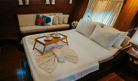 A cabin with a large bed, wooden accents, and two throw pillows on a yacht