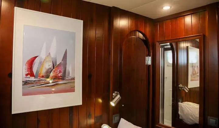 Cozy cabin interior with wood paneling, framed artwork, and curved shower door
