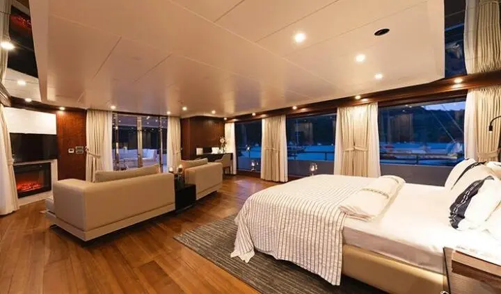 King bed in master cabin of yacht Ocean Breeze with ensuite door and warm lighting