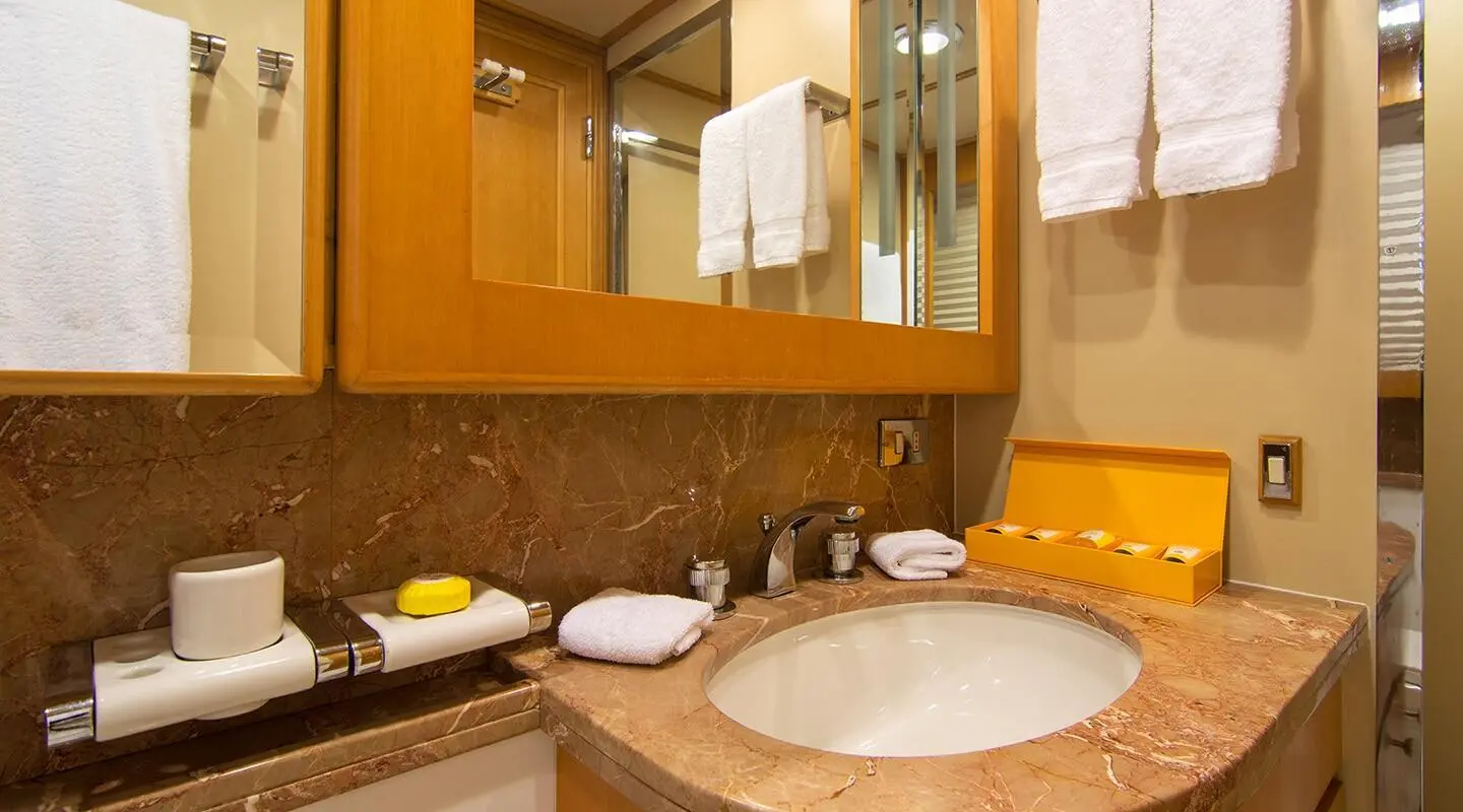 Luxurious yacht bathroom vanity with sink, mirror, towels and wooden cabinetry