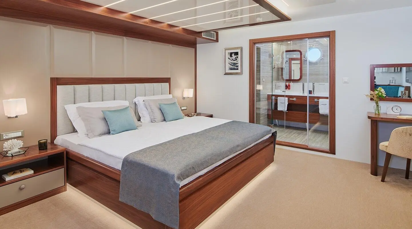 Luxurious yacht interior with a large bed, wooden accents, and seating area