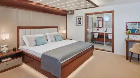 Luxurious yacht interior with a large bed, wooden accents, and seating area