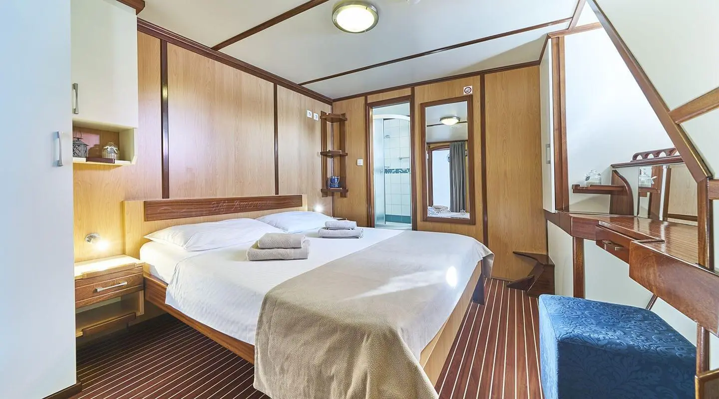 Interior of Amorena luxury yacht: wood paneling, bed, and large windows