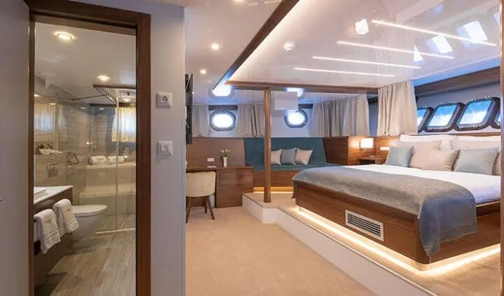 View of a yacht master cabin with king bed, ensuite, wood finishes, and bedside lamps