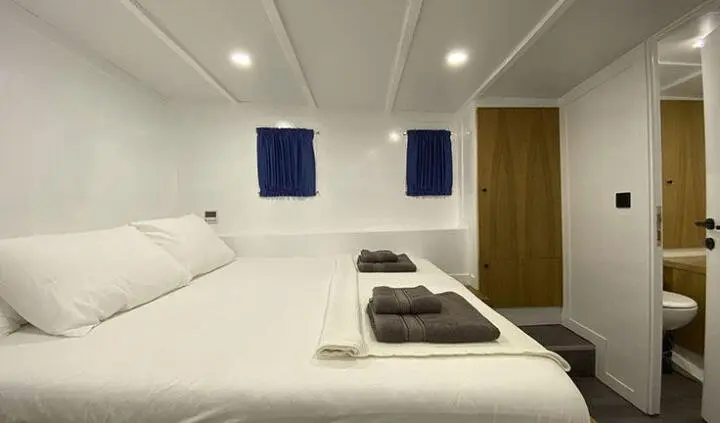 Maske 5 master cabin aboard yacht showing two single beds and blue curtains