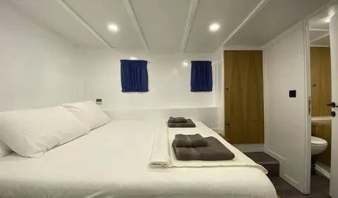 Maske 5 master cabin aboard yacht showing two single beds and blue curtains
