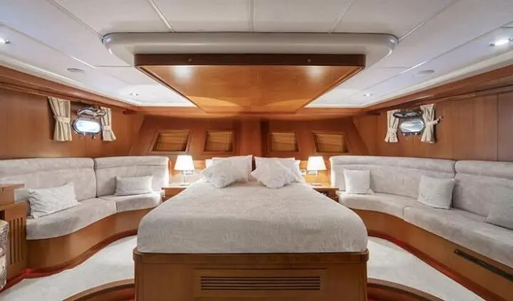 Master cabin with king bed, wood panels, and ensuite glimpse