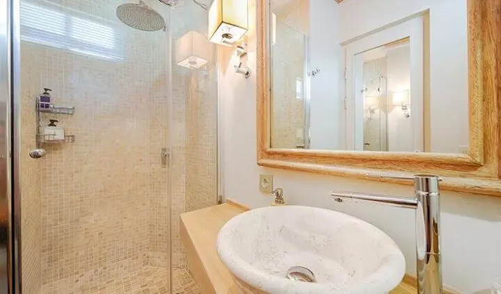 Cobra King cabin interior with glass shower, stone basin, and warm wooden frame mirror