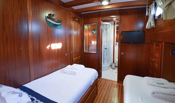 Twin cabin with wooden gloss panels, two single beds, small doorway