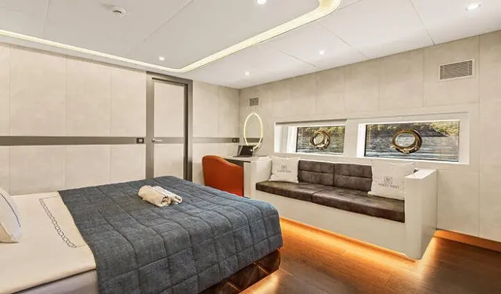 North Wind yacht cabin with a bed, desk, seating area and warm lighting