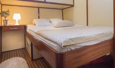 Altair yacht cabin interior with plush bed, wooden furniture, and bedside lamp