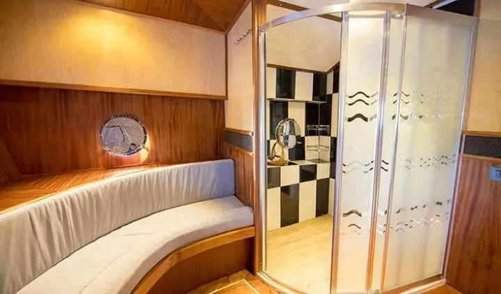 Nevra Queen master cabin with king bed, wood panels, ensuite door visible